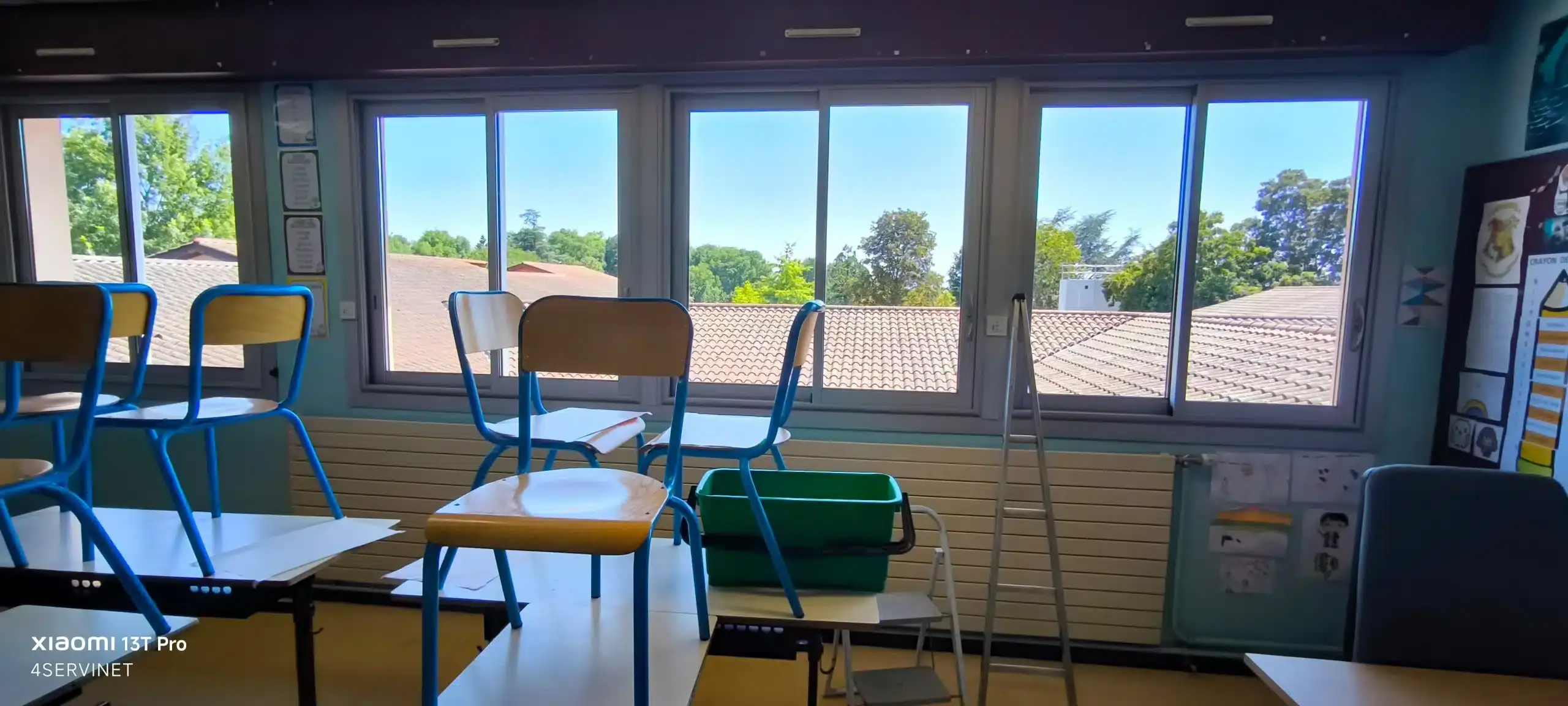 Photo illustrant le nettoyage de vitres à Lyon : un professionnel utilise un seau, une raclette et une échelle pour nettoyer une vitre.